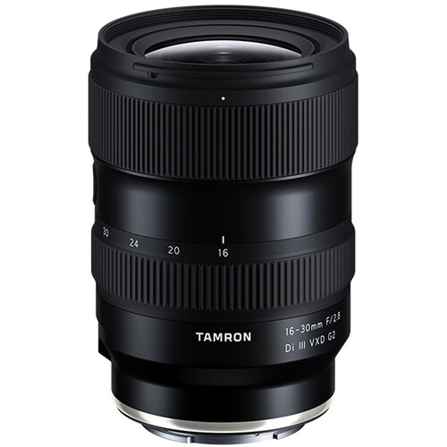 Ein Fotograf hält eine Kamera mit dem Tamron 16-30mm F2.8 G2 Objektiv für Sony E-Mount und nimmt eine weite Stadtlandschaft bei Sonnenuntergang auf.